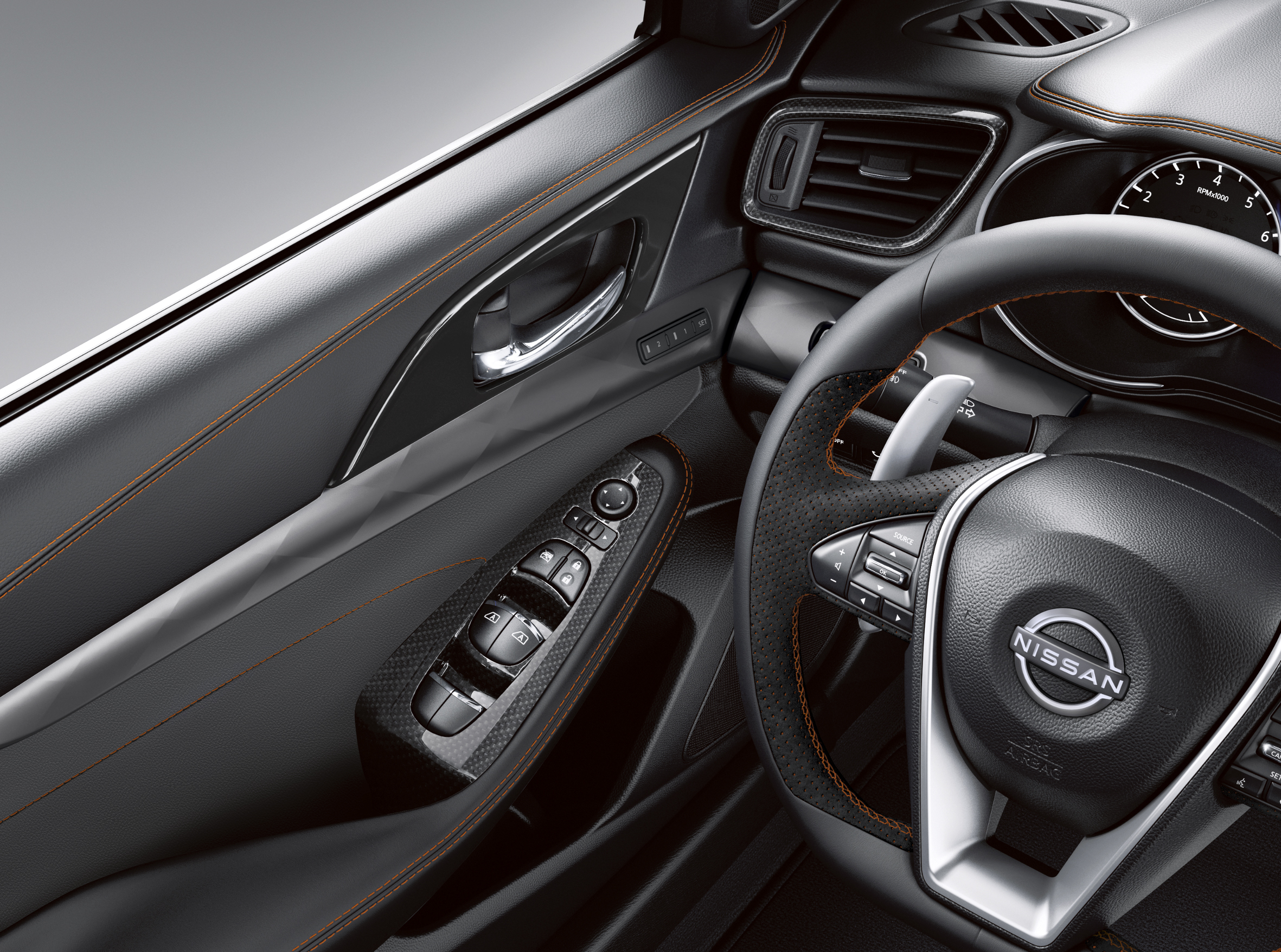 L'intérieur d'une Nissan Maxima montre le volant et le panneau de commande sur la porte.  Les deux disposent d’un ensemble de boutons contrôlant les fonctionnalités de la voiture.